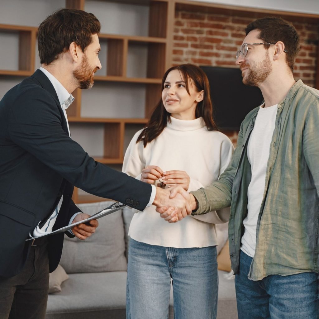 A real estate agent shaking hands with a client in front of a modern property, symbolizing trust and partnership.